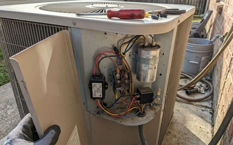 Hard-start kit and capacitor inside an outdoor unit electrical compartment