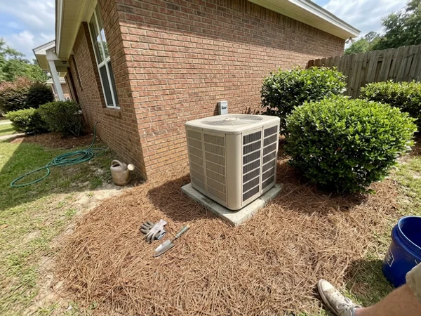 Outdoor AC unit with clear space around it beside a brick home