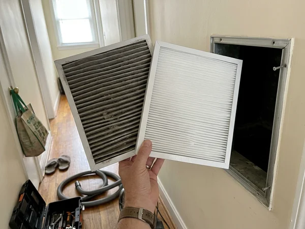 Dirty air filter held next to a clean new filter