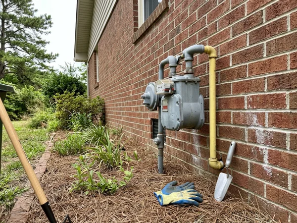 Gas meter and gas line at the side of a brick home