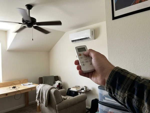 Hand holding a mini-split remote in a bonus room