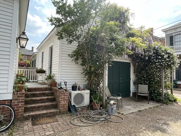 Carriage house with a small mini-split condenser beside the steps