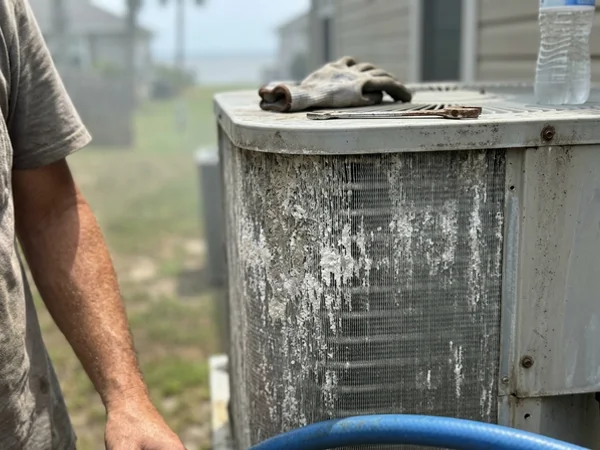 Salt crust on the aluminum fins of an outdoor AC unit near Mobile Bay